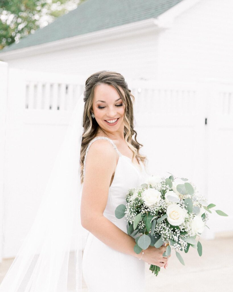 bride in long veil holding white and green bouquet