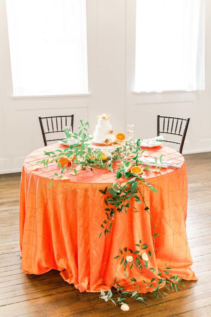 orange citrus wedding inspiration sweetheart table decorated with greenery