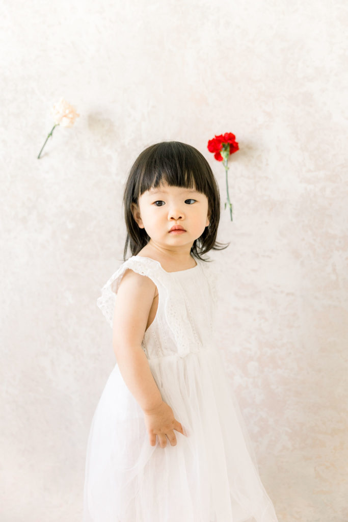 best Midland Michigan family photographer toddler with carnation backdrop