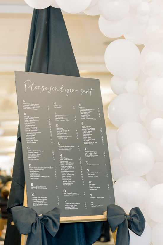 Black and white wedding reception seating chart with balloon arch