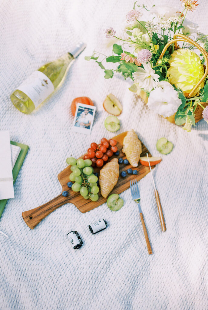 Charcuterie board picnic on a blanket with flower basket