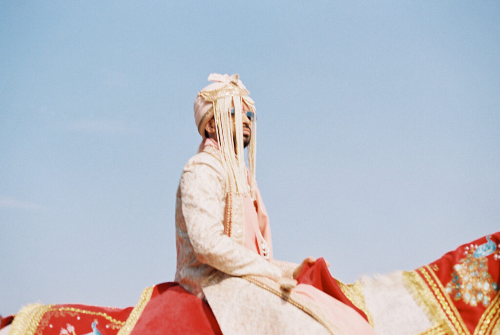 Hindu wedding groom riding baraat horse decorated with gold and red