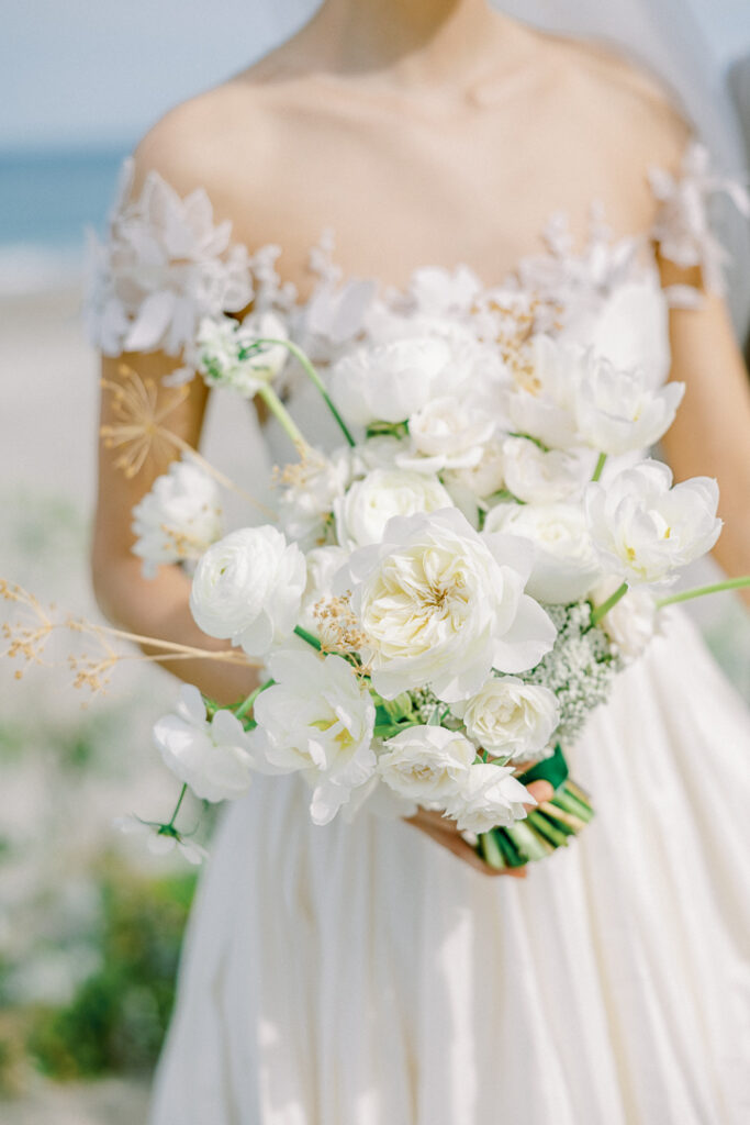 bride in ivory wedding dress holding white flower bouquet